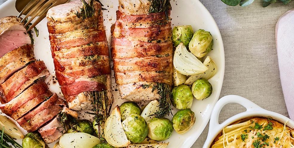 In spek en kruiden gerold varkenshaasje met geroosterde spruiten en aardappel-knolseldergratin