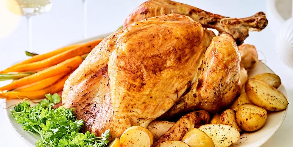 Klassiek geroosterde en gevulde kalkoen met honingworteltjes, krieltjes en vleesjus