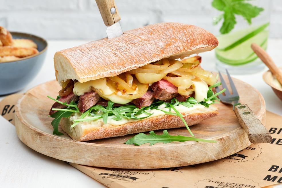 Steaksandwich met gekarameliseerde ui, lookdressing en ovenfrietjes