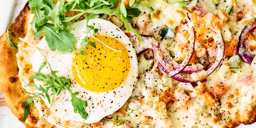 Gegrild flatbread belegd met roomkaas, restje groenten, mozzarella en eitje